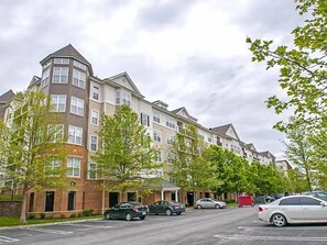 A row of multi-story residential buildings with a parking lot in front. - Landing | Incredible 2BD, Gym, Pool (King of Prussia)
