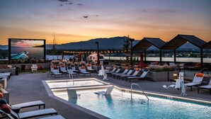 Ein Poolbereich mit Liegestühlen, einem Pool und einer großen Leinwand, die einen Sonnenuntergang zeigt.