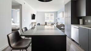 Una cucina moderna con isola centrale, mobili scuri e un'ampia finestra che permette l'illuminazione naturale.