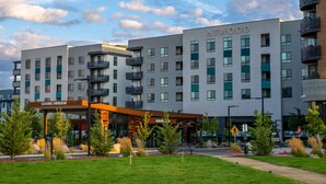 A multi-story building with 'ATWOOD' signage, a LEASING PAVILION, and a pedestrian pathway with greenery. - Landing | Incredible 1BD, Clubhouse, Courtyard (Reno)