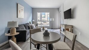 A modern living room with a sofa, a round table, and a TV mounted on the wall. - Landing | Incredible 1BD, Clubhouse, Courtyard (Reno)