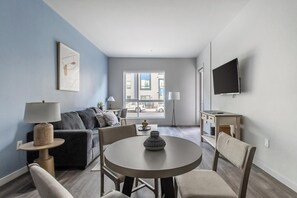 A modern living room with a sofa, a round table, and a TV mounted on the wall. - Landing | Spectacular 1BD, Courtyard, Clubhouse (Reno)