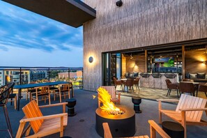 An outdoor patio with a fire pit, seating, and a view of the cityscape. - Landing | Beautiful 1BD, Clubhouse, Courtyard (Reno)