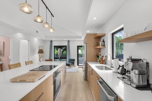 A modern kitchen with a central island, built-in appliances, and a coffee machine. - Designer Wabi Sabi Retreat - Private Gated Compound Near Design District (Miami)