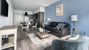 A modern living room with a sofa, coffee table, and dining area. - Landing | Stunning 1BD, Clubhouse, Courtyard (Reno)