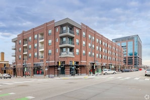 A multi-story brick building with balconies, a ground-level entrance, and a parking lot. - Landing | Chic 1BD, Clubhouse (Tulsa)