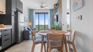 Una cocina moderna con armarios oscuros, un refrigerador empotrado y un comedor con una mesa redonda y sillas de madera.