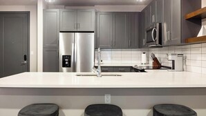 A modern kitchen with grey cabinets, stainless steel appliances, a white countertop, and a built-in oven. - Landing | Stylish 1BD, Clubhouse (Tulsa)