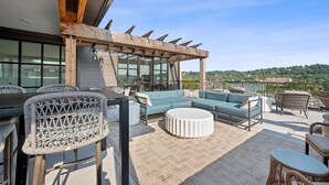 Una terraza en la azotea con zona de estar, una pérgola y vistas del paisaje.