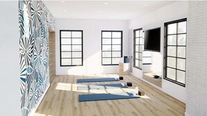 Ein Zimmer mit großen Fenstern, Holzboden und Trainingsmatten.