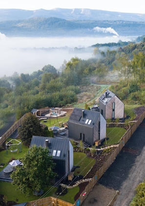 A modern house with a large deck, a swimming pool, and a view of the surrounding forest and mountains. - Flowfort View Private Hottub & Sauna Dom Swobodnie (Stara Kamienica)