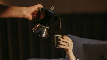 A person pouring a drink into a cup on a bed.