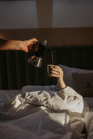 A person pouring a drink into a cup on a bed. - Flowfort View Private Hottub & Sauna Dom Swobodnie (Stara Kamienica)