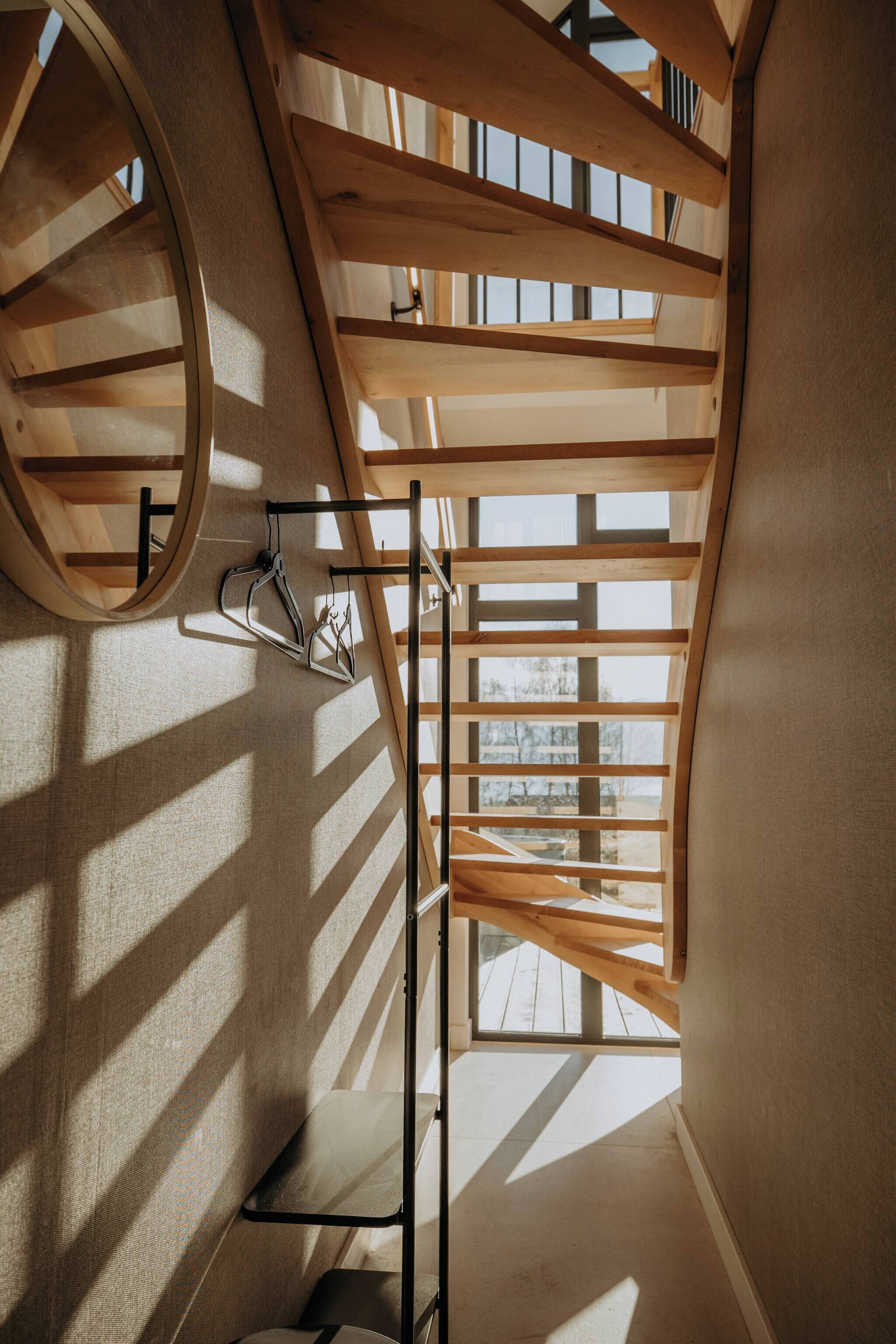 A spiral staircase with wooden beams and a circular window.