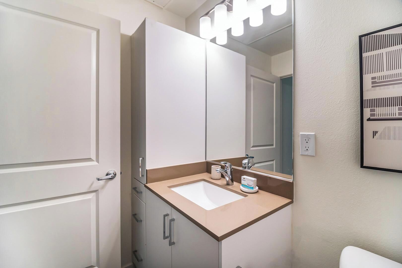 Une salle de bain avec un lavabo blanc, un miroir et un meuble.