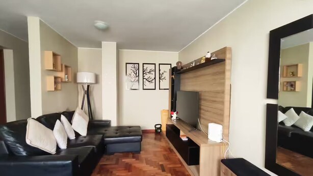 Un soggiorno moderno con un divano, una televisione e un mobile porta TV in legno.