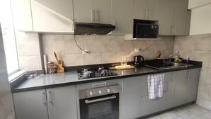 Una cucina moderna con mobili grigi, forno integrato, microonde e piano cottura a gas.