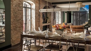 A dining area with a brick wall, large windows, and a table set for six. - Historic Diplomat Suite w/Parking - The Harmony (Philadelphia)