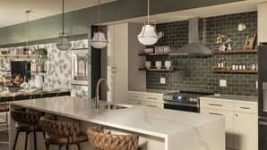 A modern kitchen with a large island, pendant lights, and a backsplash. - Historic Diplomat Suite w/Parking - The Harmony (Philadelphia)