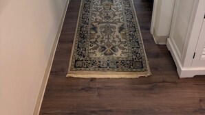 A hallway with a patterned rug, a door leading outside, and a garage door visible through the window. - Perfect 2-bedroom house with AC in peaceful Jamestown w/ RV pad (Jamestown)
