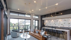 Un espacio de estar moderno con un sofá de cuero, una mesa de centro redonda y una cocina con taburetes de bar.
