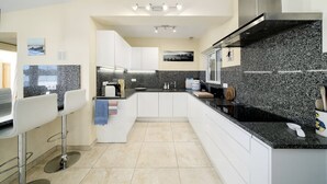 A modern kitchen with white cabinets, granite countertops, and stainless steel appliances. - Casa Descoberta - Luxurious 4 Bedroom family Villa with heated pool (Carvoeiro)