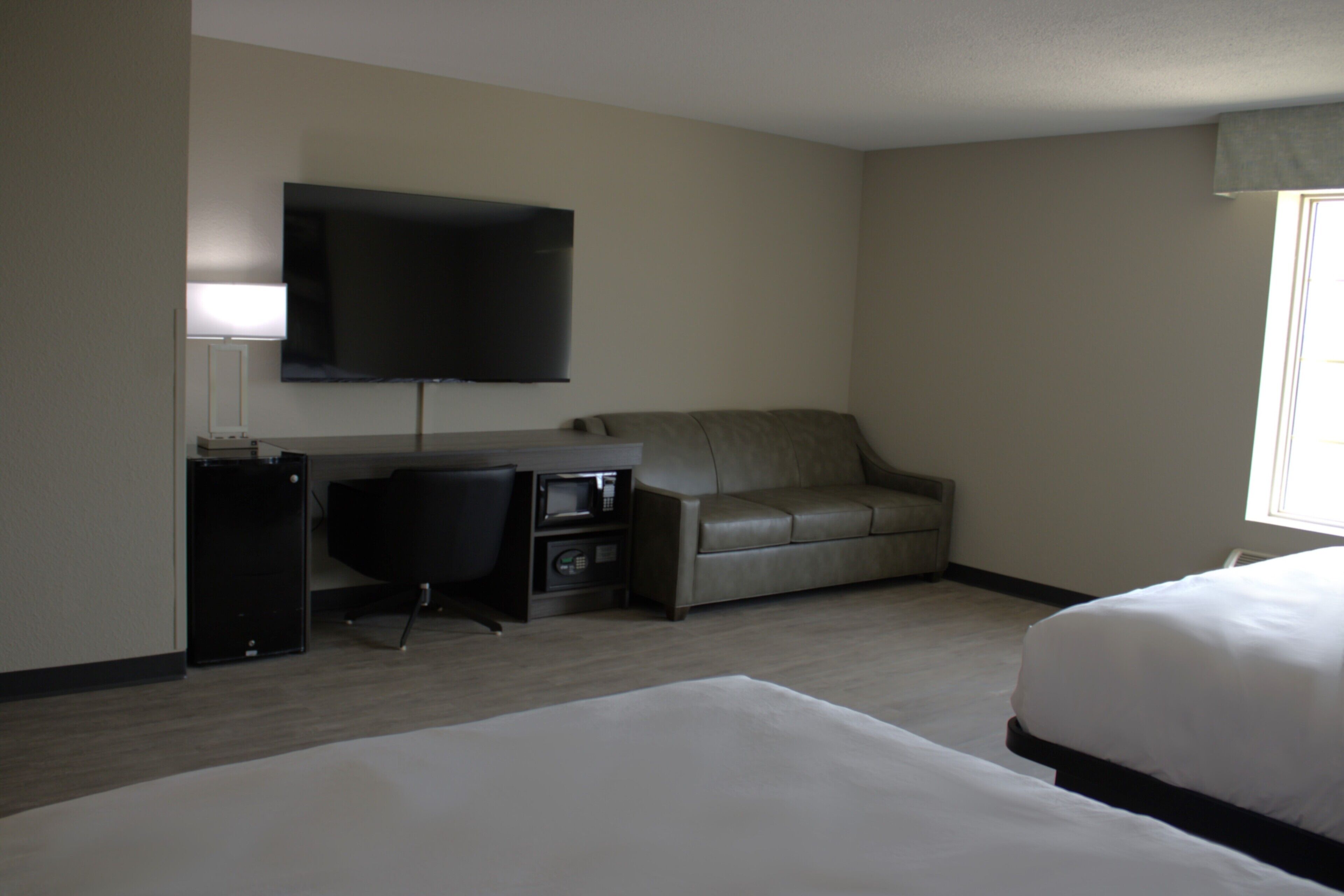 A hotel room with a bed, a desk with a computer, a television, and a sofa.