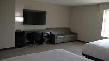 A hotel room with a bed, a desk with a computer, a television, and a sofa.