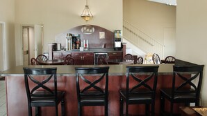 Une cuisine avec un coin bar, des chaises en bois et un escalier.