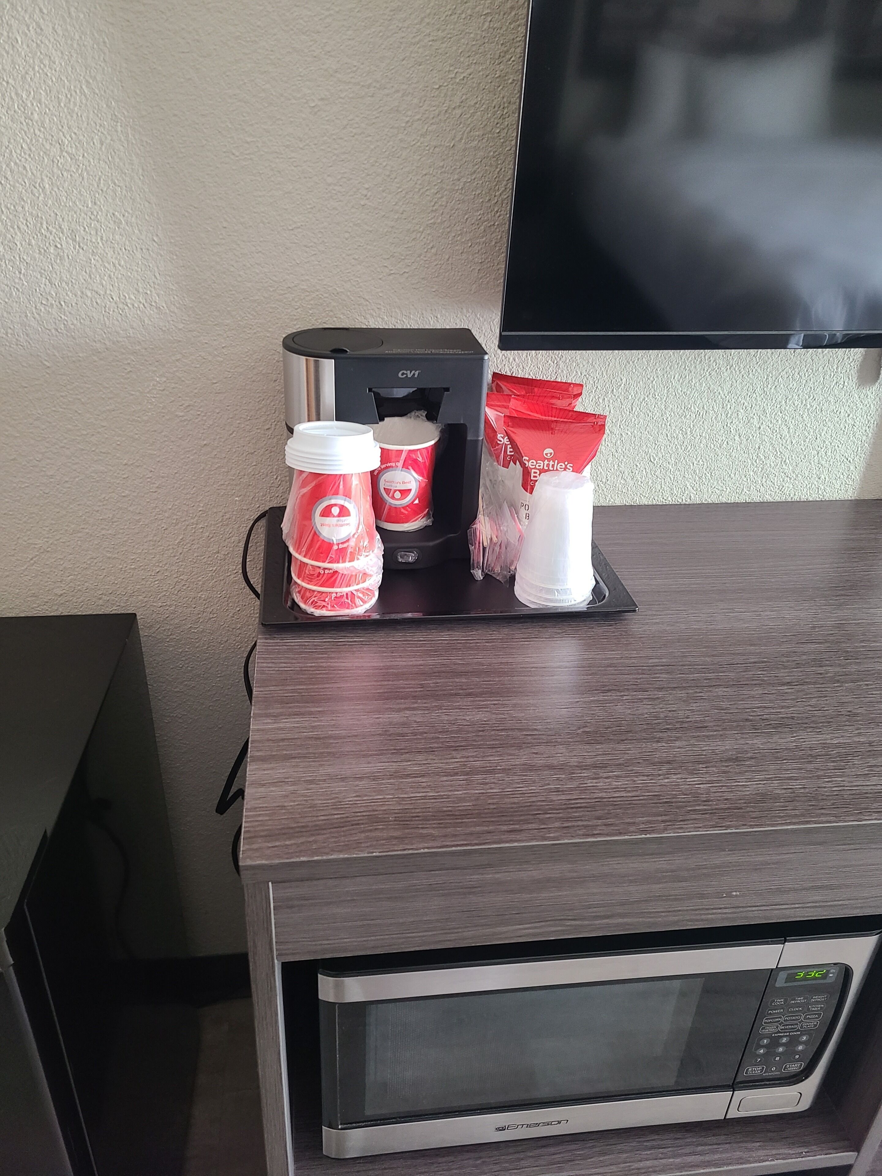 A microwave oven, a coffee maker, and a bottle of water on a wooden counter.