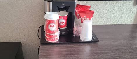 A microwave oven, a coffee maker, and a bottle of water on a wooden counter.