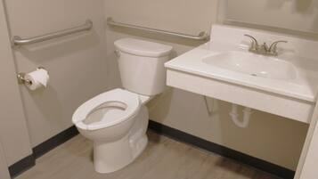 Une salle de bain équipée de toilettes, d’un lavabo et d’une barre d’appui.