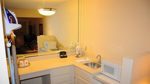 Une petite salle de bain d’hôtel équipée d’un lavabo, d’un miroir, d’un four à micro-ondes et d’une machine à café.