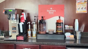 Un espace dédié au café, équipé d’une machine à café, avec une option de café décaféiné, et d’une pancarte indiquant « Le meilleur café de Seattle ».