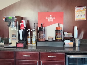 A coffee station with a coffee machine, decaf option, and a sign stating 'Seattle's Best Coffee.' - Boarders Inn & Suites by Cobblestone Hotels - Lamar (Lamar)