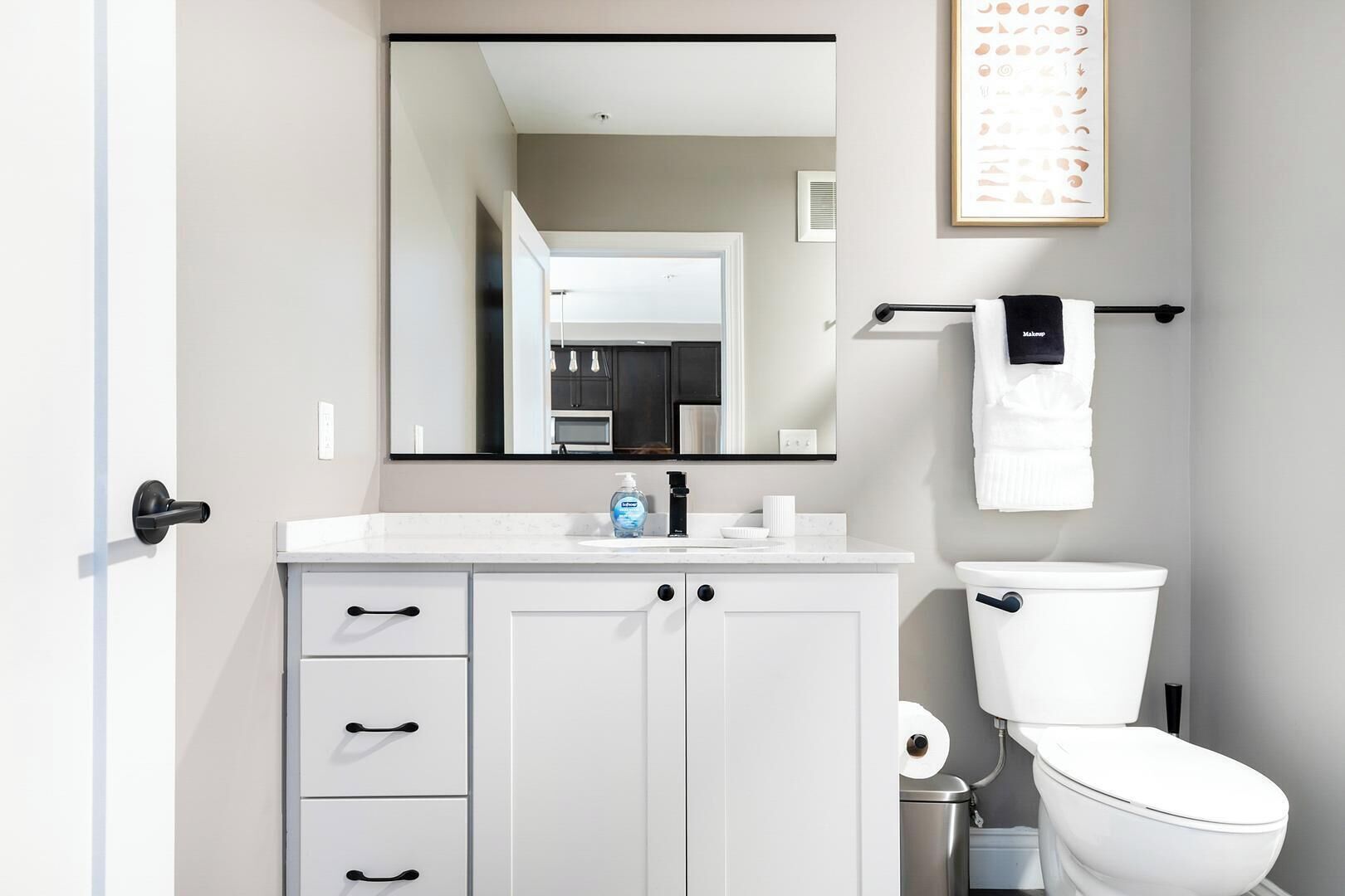 Ein modernes Badezimmer mit Waschbecken, Spiegel, Toilette und Handtuchhalter.