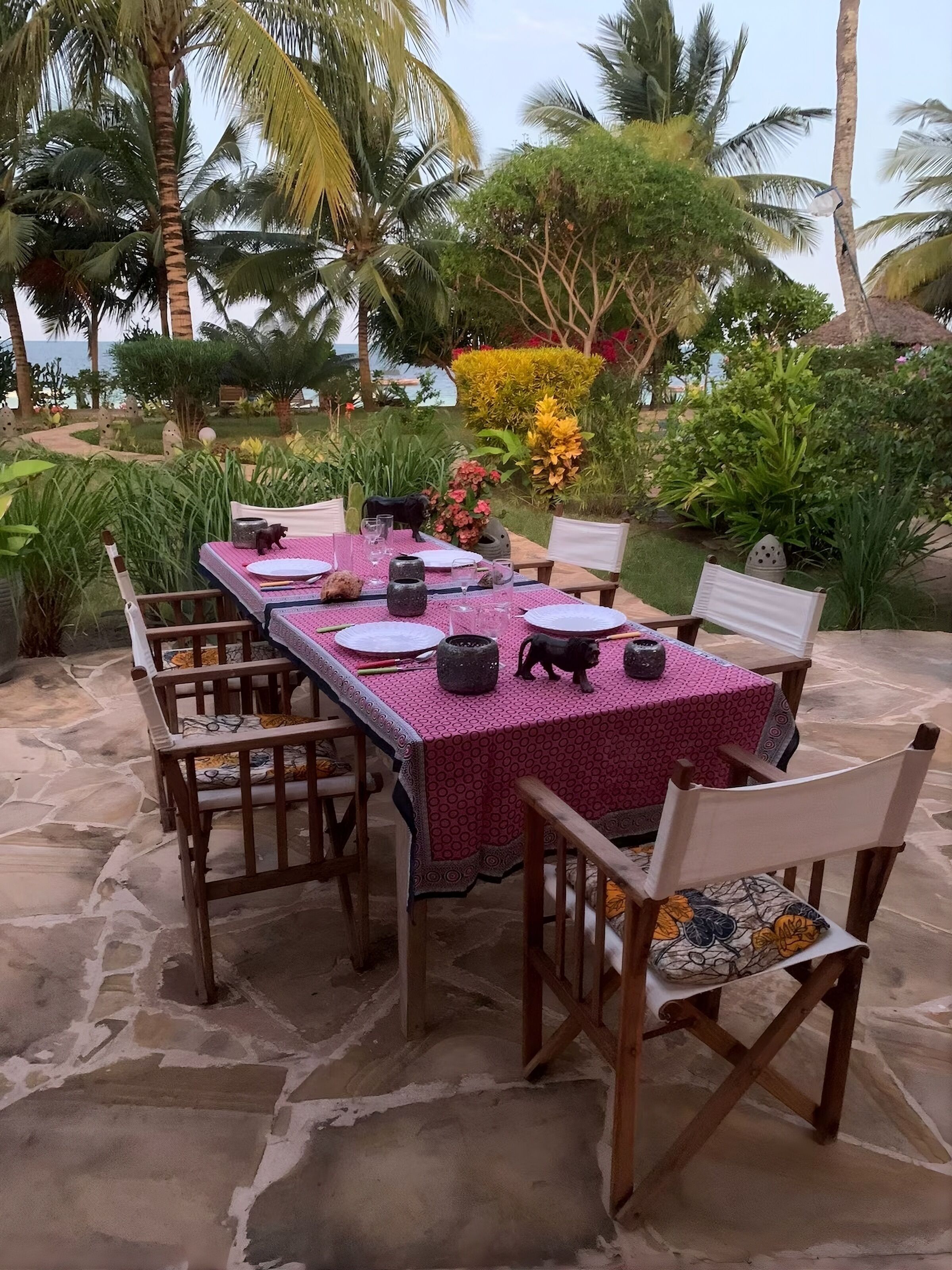 An outdoor dining area with a table set for four, surrounded by wooden chairs with cushioned seats.