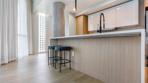 Une cuisine moderne avec un coin bar, des meubles en bois et une grande fenêtre.