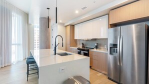 Une cuisine moderne dotée d’un îlot central, d’appareils électroménagers en acier inoxydable et de meubles de rangement en bois.