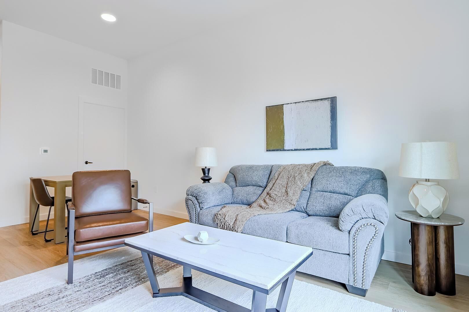 Een moderne woonkamer met een bank, een salontafel, een stoel en twee lampen.