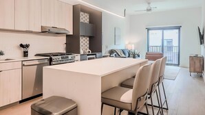 Una cocina moderna con una isla central, electrodomésticos integrados y vistas al exterior.