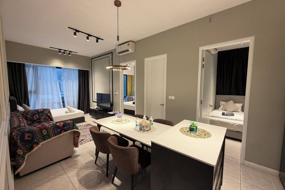 Ein modernes Hotelzimmer mit einer Couch, einem Esstisch, einem Fernseher und einem Bett.