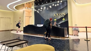 Una reception hotel dal design moderno, con pavimento in marmo e zona accoglienza caratterizzata da una palette di colori nero e oro.