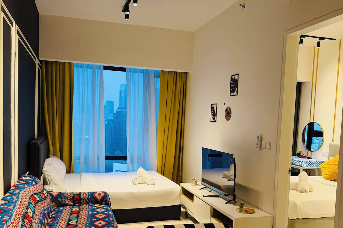 Ein Hotelzimmer mit Bett, Nachttisch, Fernseher und Blick auf die Stadtlandschaft durch das Fenster.