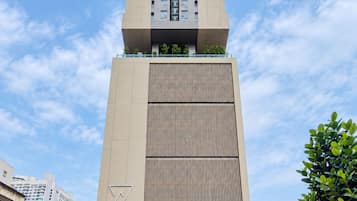 A tall, modern building with a central atrium and a lower section with a patterned facade.