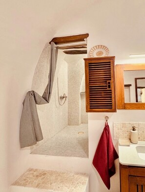 A bathroom with a shower, a wooden cabinet, a mirror, and a sink. - Favorite apartment in Pigna (Pigna)