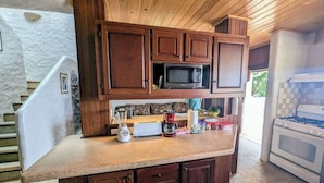 A kitchen with wooden cabinets, a microwave, a blender, a coffee maker, and a stove. - Villa Vista--Luxury Private Beachfront Villa with Spectacular Views! (Calibishie)
