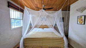 A room with a bed under a canopy, a window, and a ceiling fan. - Villa Vista--Luxury Private Beachfront Villa with Spectacular Views! (Calibishie)