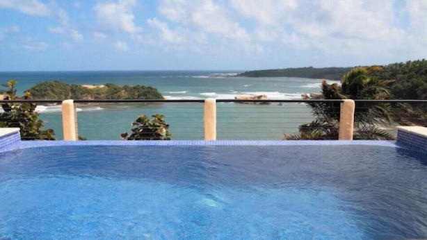 A swimming pool with a view of the ocean and a distant coastline. - Villa Vista--Luxury Private Beachfront Villa with Spectacular Views! (Calibishie)