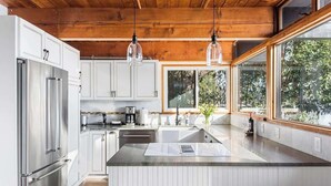 A modern kitchen with stainless steel appliances, a large island, and wooden ceiling beams.